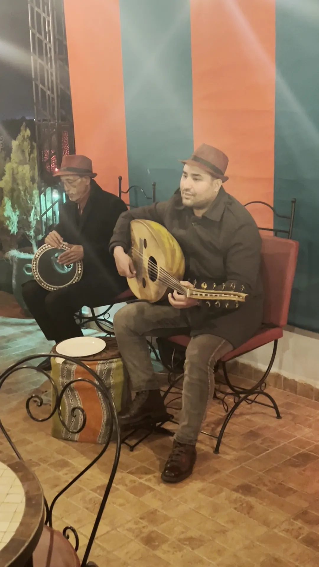 A musician playing the oud between the terrace tables