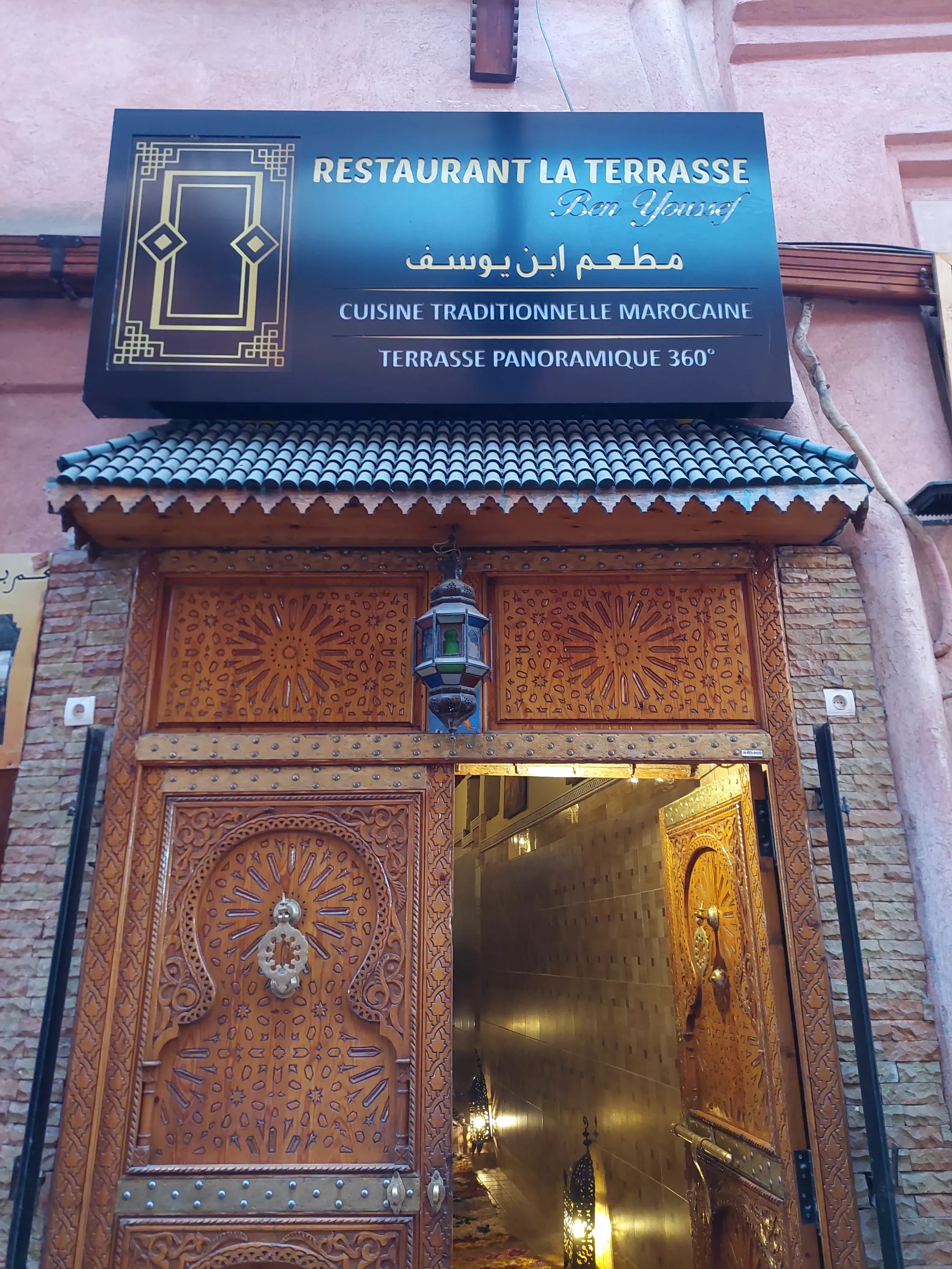 Carved wooden door beneath the blue sign on Rue Sidi Abdellaziz